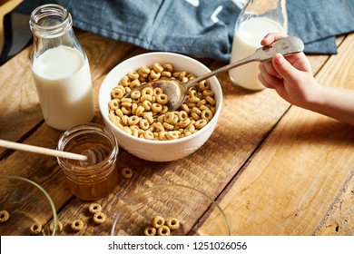 Kids Hand Holding Bowl With Healthy Breakfast With Flakes Honey Milk And Honey Dipper On Old Wooden Table