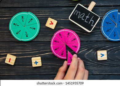 Kids hand moves colorful math fractions on dark wooden background or table. Interesting creative funny math for kids. Education, back to school concept. Geometry and mathematics materials. - Shutterstock ID 1451935709