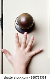 Kid's Hand Reaching Up For The Door Knob To Open It 