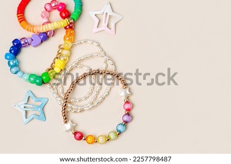 Kids handmade beaded jewelry. Necklaces and bracelets made from multicolored beads and pearls on a pastel background. DIY Multi-colored bracelet beads. Children's needlework