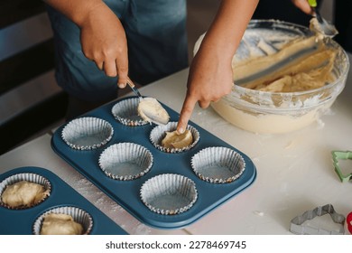 Kid's hands having fun cooking baking muffin at home together, enjoy weekend play with small children doing bakery cooking in kitchen. People lifestyle portrait - Powered by Shutterstock