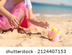 Kids hands on Easter egg hunt on the sandy beach. Happy Easter holidays concept 