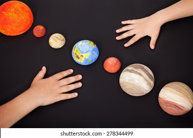 Kids Hands With The Planets Of The Solar System - Science Home Project, Focus On Earth