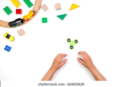 Kids Hands Playing With Fidget Spinner Toy. Many Colorful Toys On White Background. Top View