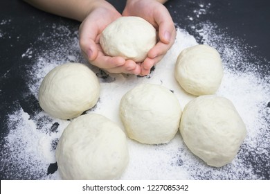 Kid's hands, some flour an wheat dough  on the black table. Children hands making the rye dough for backing bread or pizza. Small hands with dough. Little child preparing dough for backing pie