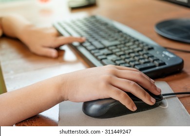 Kid's Hands using computer on desk wood. - Powered by Shutterstock