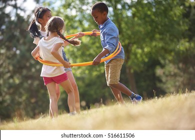 Kids happily playing with hula hoop in summer