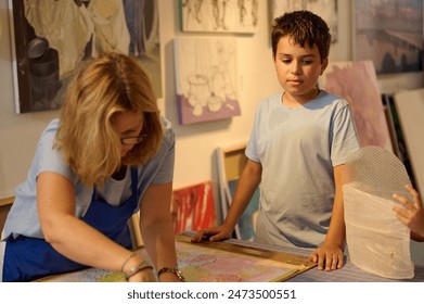Kids have art class, drawing, painting with teacher in workshop. The image shows a teacher guiding a child in an art activity, fostering creativity and learning. - Powered by Shutterstock