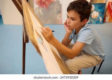 Kids have art class, drawing, painting with teacher in workshop. Young boy is deeply focused on his artwork, showing creativity and concentration - Powered by Shutterstock