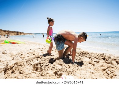 Kids having fun at the beach on a sunny day, building sandcastles and playing with sand and water. - Powered by Shutterstock