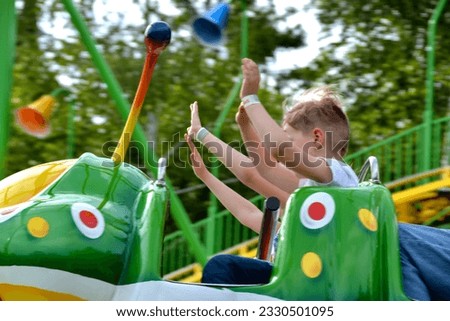 Kids having fun in ferris wheel with chains, carousel ski flyer in amusement park. Happy children, twins having fun outdoors on sunny day. High quality photo