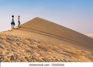 Kids Having Fun Playing Together At Sand Dunes In Qatar Desert