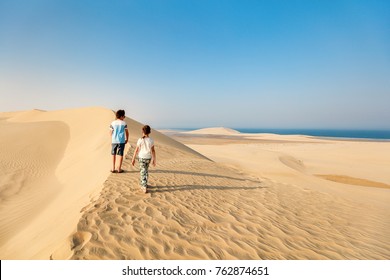 Kids Having Fun Playing Together At Sand Dunes In Qatar Desert