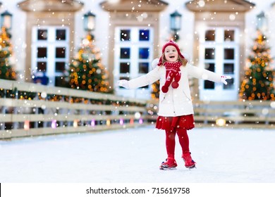 Kids Ice Skating In Winter Park Rink. Children Ice Skate On Christmas Fair. Little Girl With Skates On Cold Snowy Day. Snow Outdoor Fun For Child. Winter Sports. Xmas Vacation Activity With Kid.