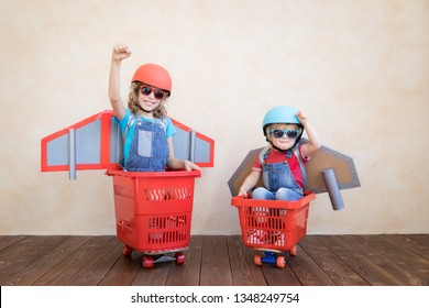 Kids With Jet Pack Racing On Shopping Cart. Children Playing At Home. Success, Imagination And Innovation Technology Concept