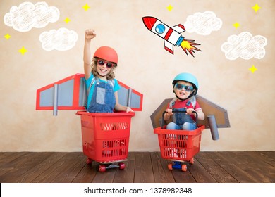 Kids With Jet Pack Racing On Shopping Cart. Children Playing At Home. Success, Imagination And Innovation Technology Concept