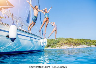 Kids Jump In Sea Of Sailing Yacht On Summer Cruise. Travel Adventure, Yachting With Child On Family Vacation.