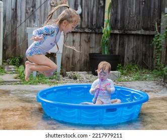 Kids Jumping In A Kiddie Pool In The Backyard. Summer Fun With Water Play 