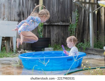 Kids Jumping In A Kiddie Pool In The Backyard. Summer Fun With Water Play