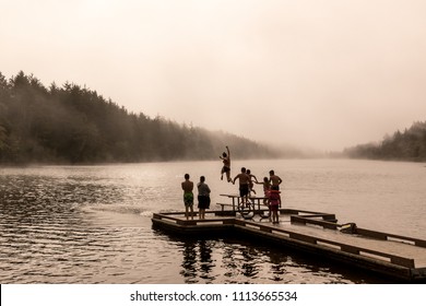 Kids Jumping Off A Dock Into A Lake With Fading Light 