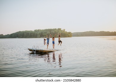 Kids Jumping Off Dock Into Lake At Sunset 