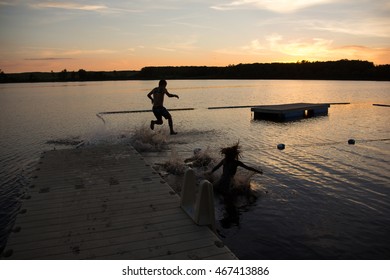 Kids Jumping Off Dock At Sunset
