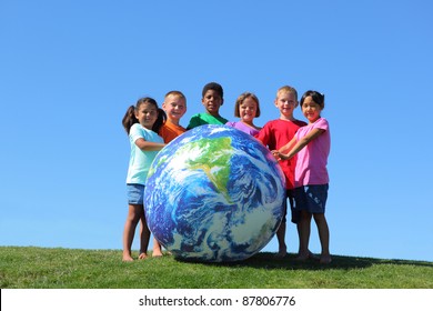 Kids with large earth ball, on grass hill with blue sky