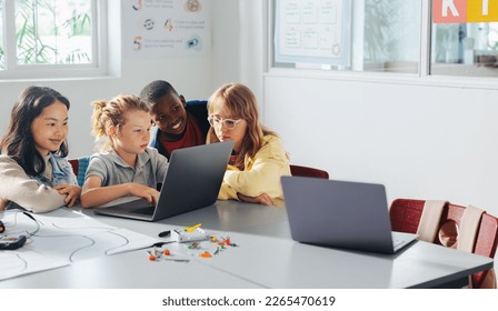 Kids learning to program robots in a computer-based STEM classroom, working together to build and operate robotic vehicles. Children using computer software to do a class project in coding school. - Powered by Shutterstock