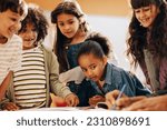 Kids learning from their teacher in school. Group of children pay attention as their teacher shows them how to draw in class. Children schooling in a co-ed education centre.