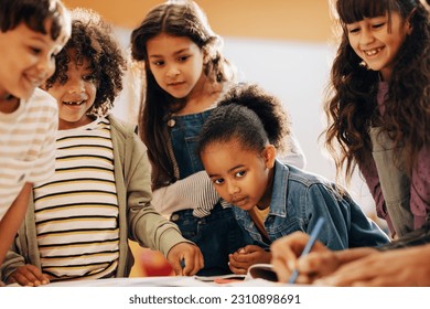 Kids learning from their teacher in school. Group of children pay attention as their teacher shows them how to draw in class. Children schooling in a co-ed education centre. - Powered by Shutterstock