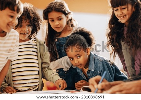 Kids learning from their teacher in school. Group of children pay attention as their teacher shows them how to draw in class. Children schooling in a co-ed education centre. Foto stock © 