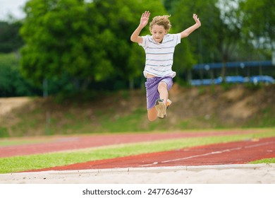 Kids long jump athletics training. Child jumping in sand pit on school stadium. Healthy outdoor exercise for children. Young athlete exercising. Sport for young boy. - Powered by Shutterstock