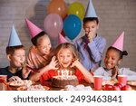 Kids looking at birthday cake with candles, having b-day party