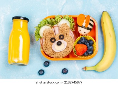 Kids lunch box with funny bear sandwich and boiled egg bee, banana, orange juice. Back to school background. Top view