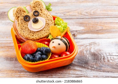 Kids lunch box with funny bear sandwich and boiled egg bee, apple, orange juice. Back to school background. Copy space - Shutterstock ID 2183886865