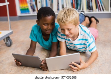 Kids Lying On Floor Using Digital Tablet In Library