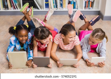 Kids Lying On Floor Using Digital Tablet In Library