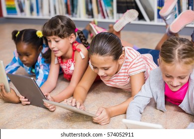 Kids lying on floor using digital tablet in library - Shutterstock ID 574052911