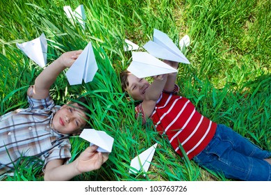 Kids Lying On Grass And Playing With Paper Planes