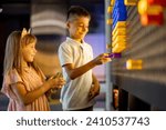 Kids making a picture with colored chips on the wall, playing on interactive models in science museum. Concept of children