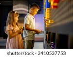 Kids making a picture with colored chips on the wall, playing on interactive models in science museum. Concept of children