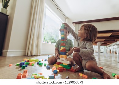 Kids Making A Tower Using Building Blocks. Happy Kids Playing With Toys Sitting On Floor At Home.