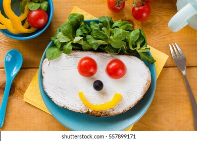 Kids Meal, Breakfast Or Lunch For Children. Colorful Funny Food Face With Healthy Vegetables, Cheese Spread And Green Salad On A Plate. Concept Of Healthy Food, Healthy Breakfast. Top View, Closeup