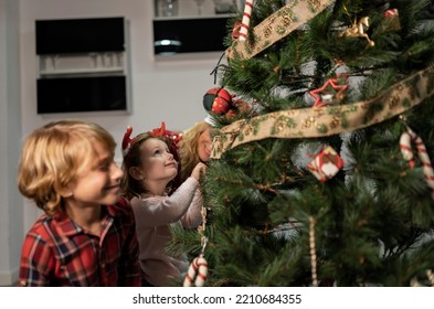 Kids With Mom Putting Up The Christmas Tree Lights - Focus On Little Girl -