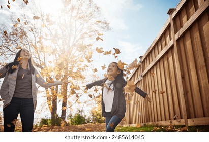 Kids, mother and girl throwing autumn leaves in garden of home together for bonding or love. Asian family, fall or smile with happy single parent and daughter having fun in backyard for wellness - Powered by Shutterstock