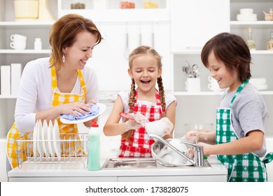 Kids and mother washing dishes - having fun together in the kitchen