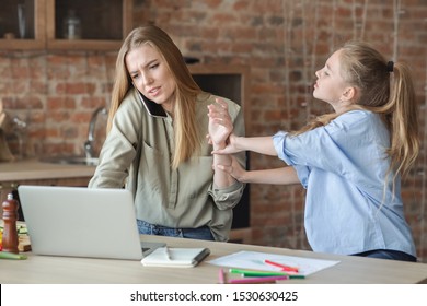 Kids Need Attention. Blondy Daughter Asking Her Busy Mom For Attention, Mother Talking By Phone And Looking At Laptop, Kitchen Interior, Copy Space