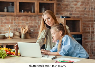 Kids Need Attention. Blondy Daughter Interrupting Her Busy Mom While Woman Talking By Phone, Using Laptop, Kitchen Interior, Copy Space