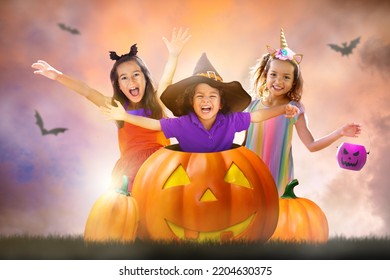 Kids On Halloween Night. Children Trick Or Treat. Multi Ethnic Group Of Kids In A Giant Pumpkin Lantern. Boy And Girl In Witch Costume And Scary Bucket.