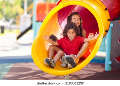 Kids on playground. Children play outdoor on school yard slide. Healthy activity. Summer vacation fun. Child playing in sunny park. Kid having fun on colorful slide.